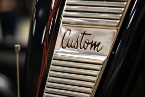 A close-up shot of a custom chrome detail on a classic car with pinstripe design.
