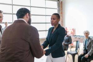 Diverse group in an office setting exchanging a handshake, symbolizing collaboration.